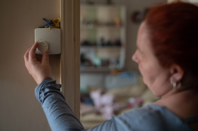 Female customer adjusting thermostat in her home