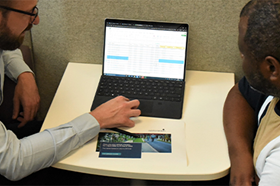 2 men looking at a laptop with service charge booklets in front of them