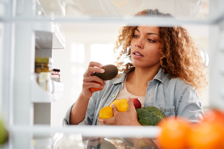 Woman storing fresh food in her fridge