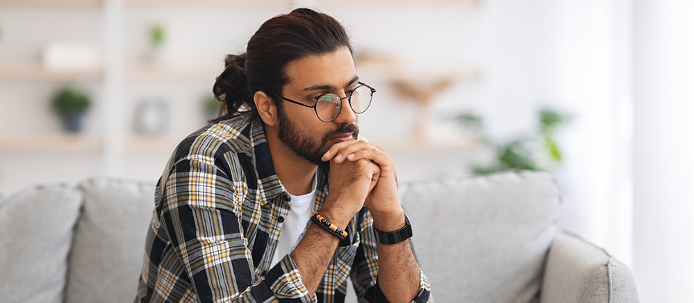 Person sitting on a couch with their head in their hands