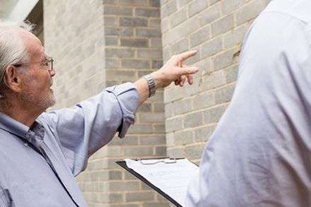 Man with a clipboard pointing at a building